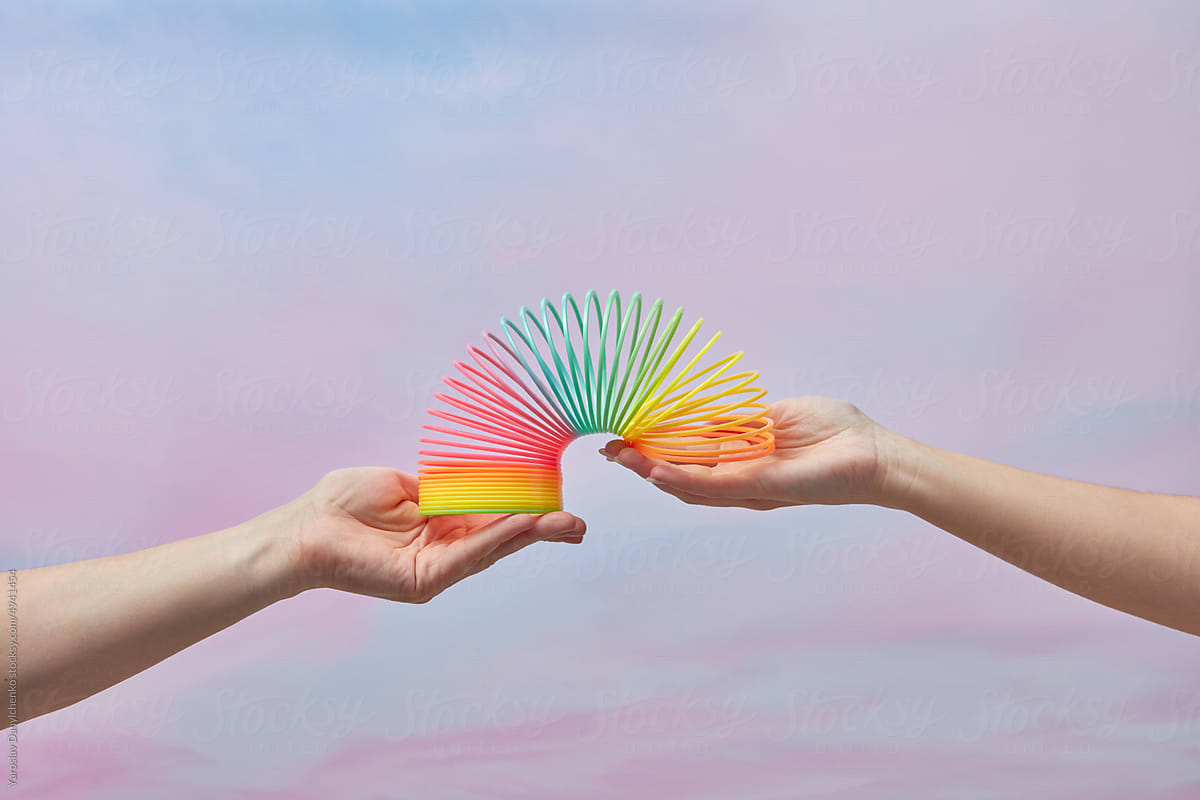 Rainbow colored spring toy held by female hands.