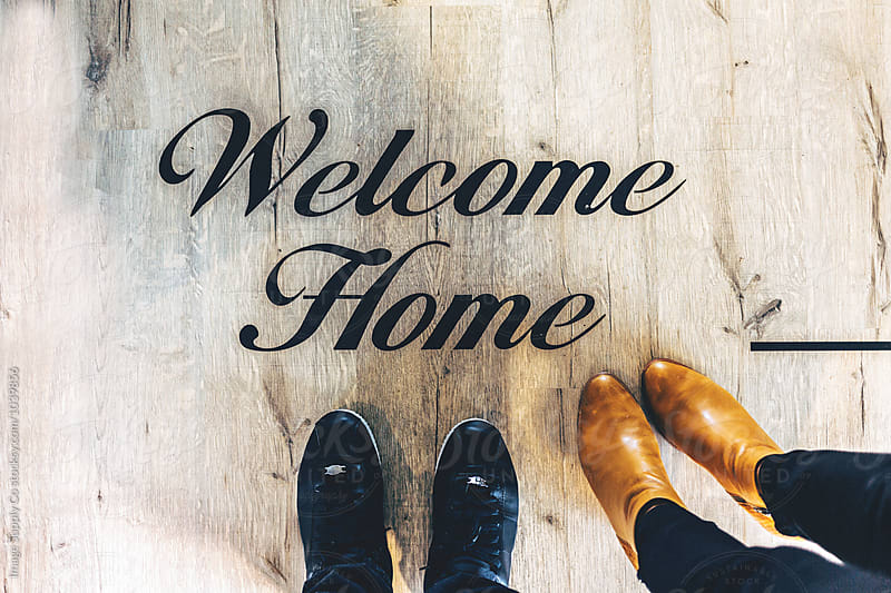Overhead shot of welcome Home sign on floor with couples legs