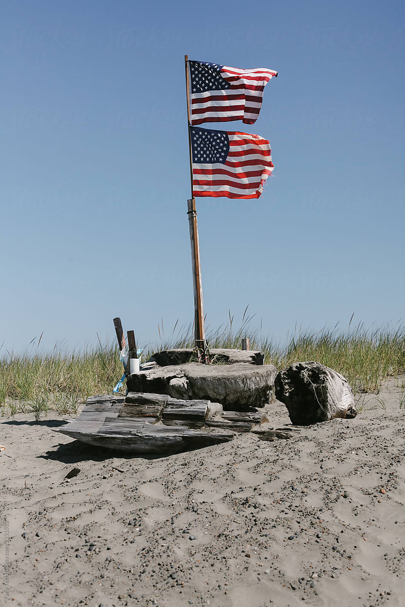 double American flag waves in wind at a beach
