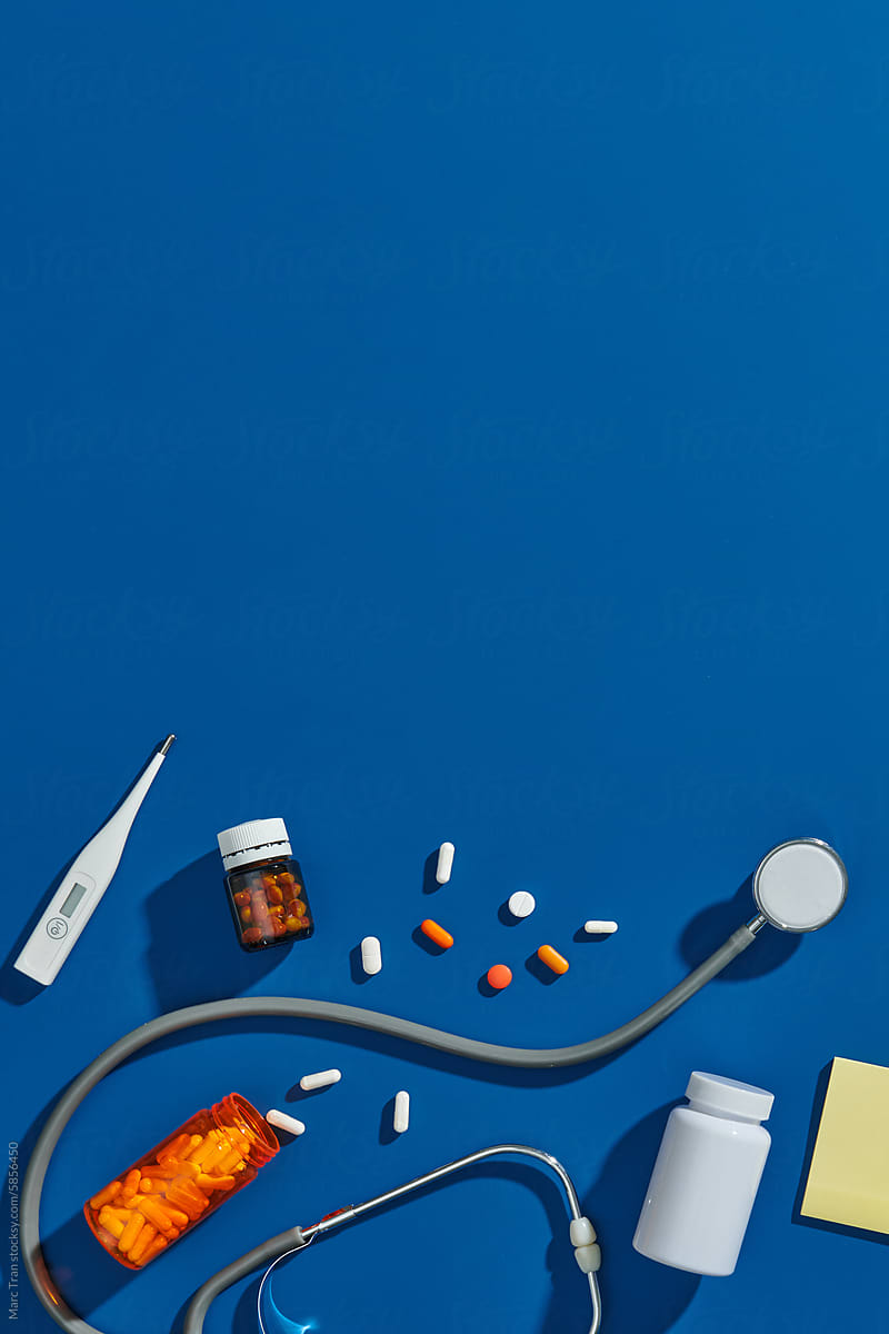 Doctor table with medical items on blue background. Flat lay