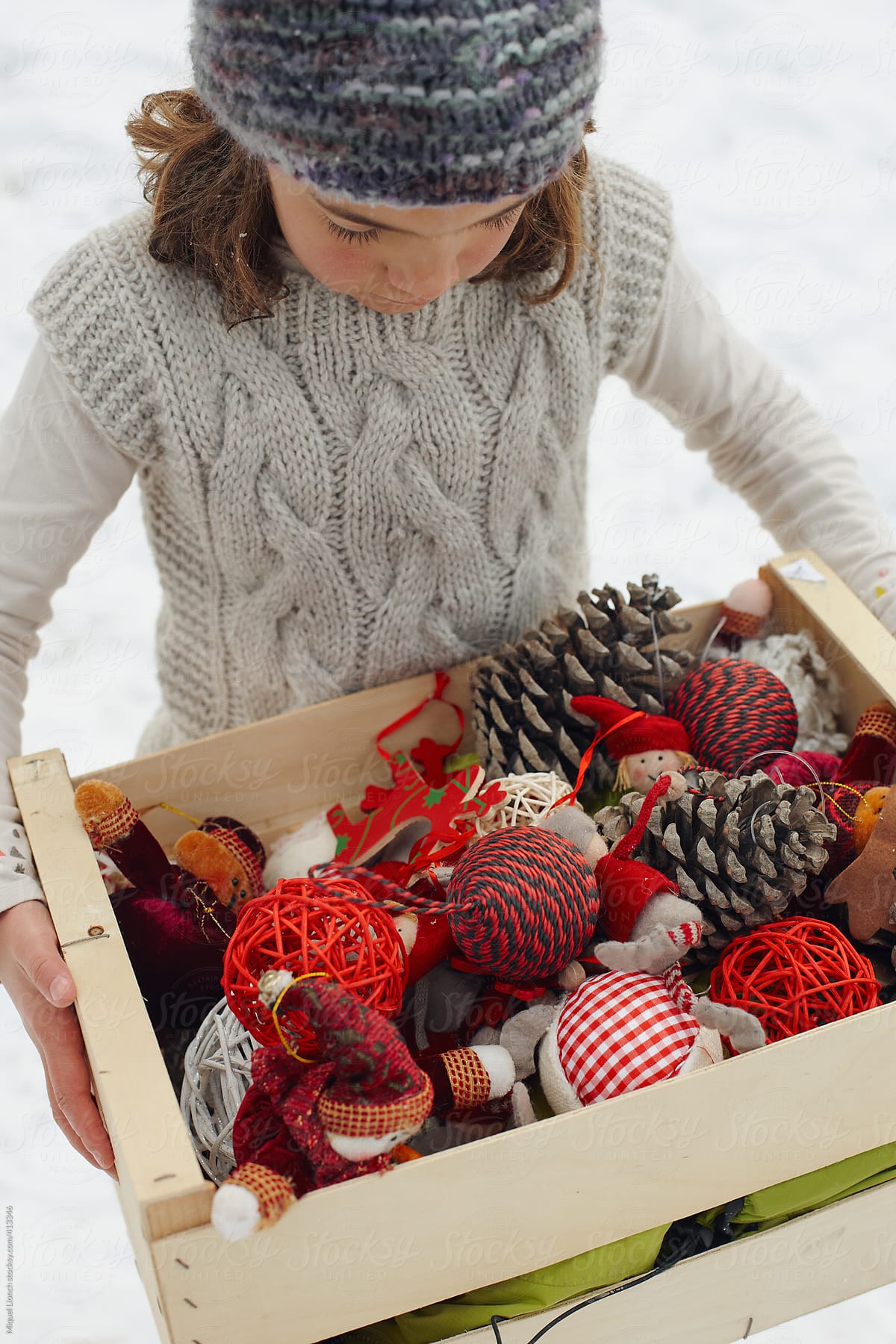 Young girl holding a box full of Christmas ornaments