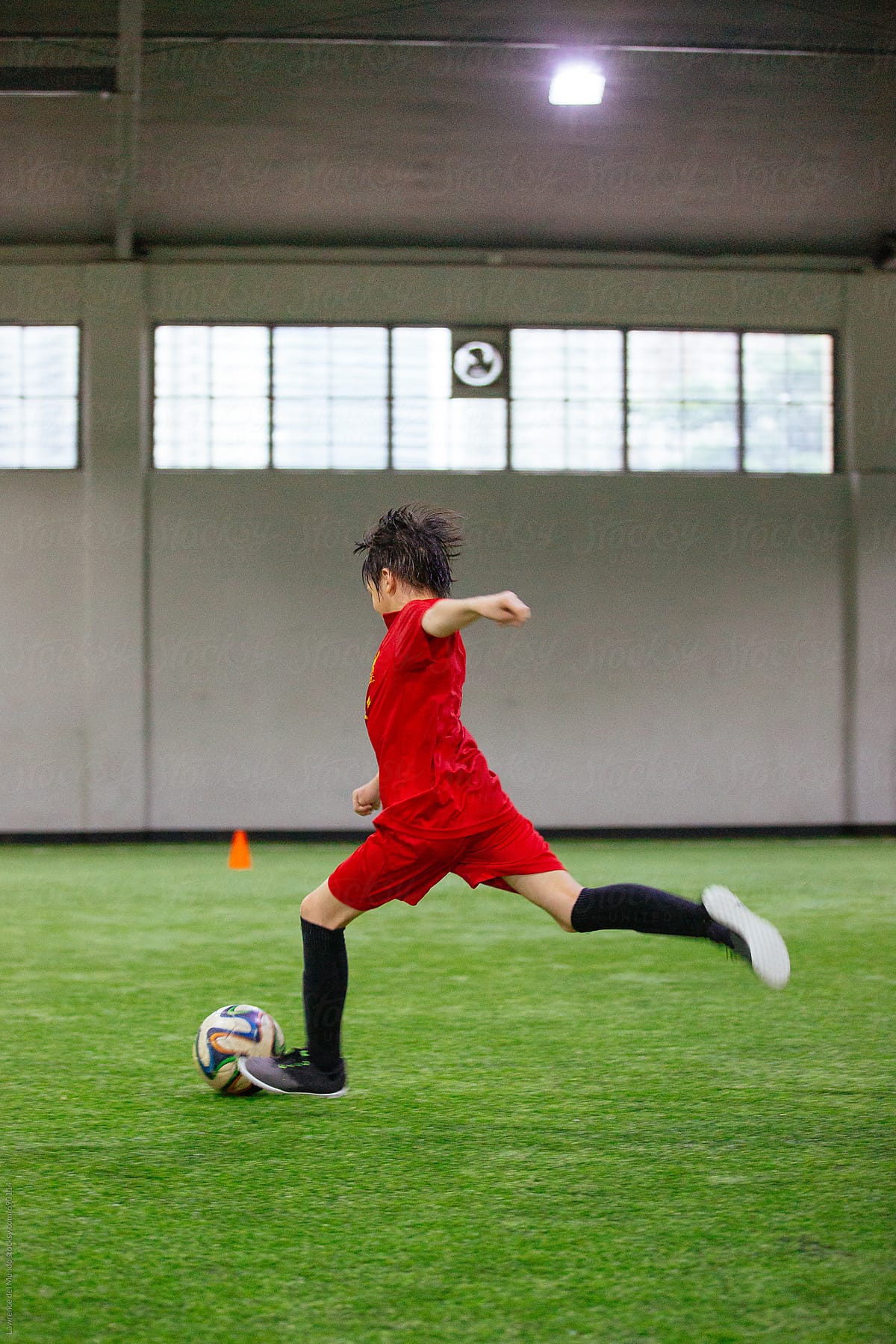 Young football player about to kick the ball in a game at an indoor ...