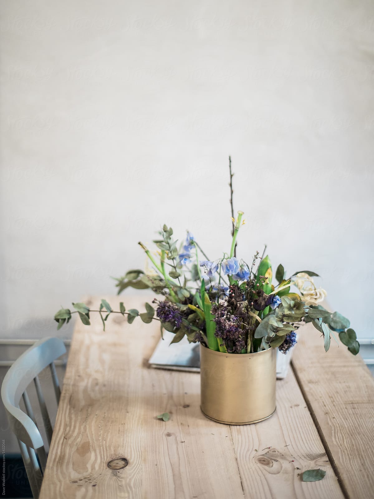 A vase of flowers sits on a rustic wood kitchen table.