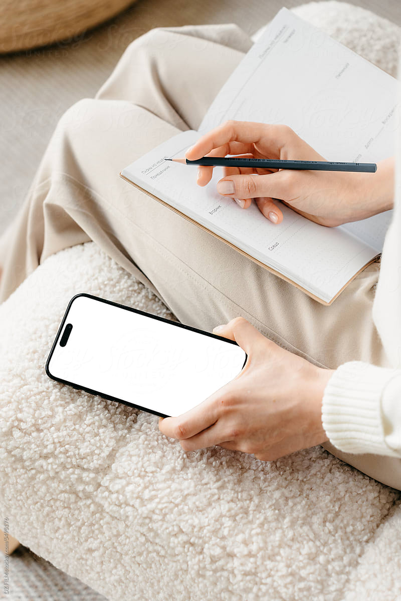 A mobile with a white screen is lying next to a woman at home