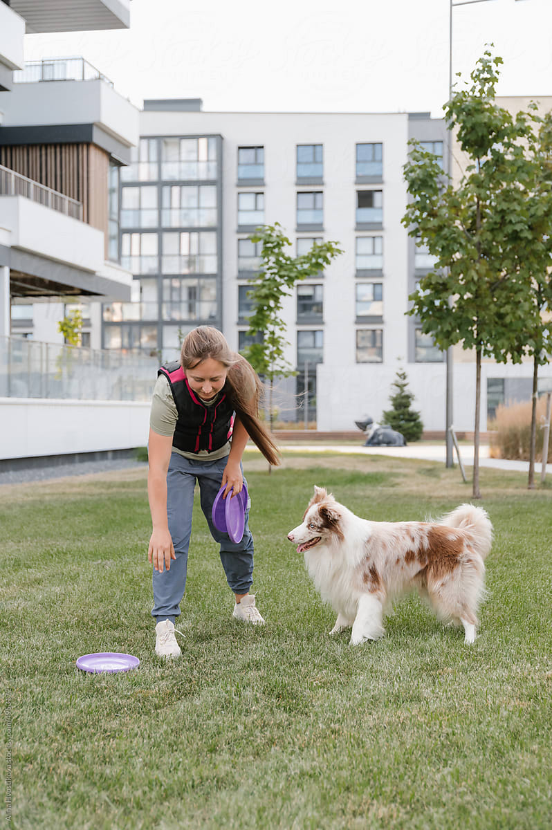Woman teaching dog to catch frisbee