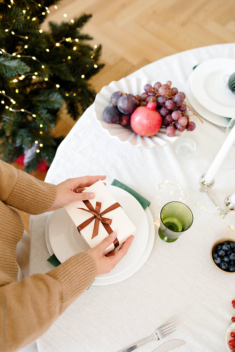 A woman packs a Christmas gift on a festive table