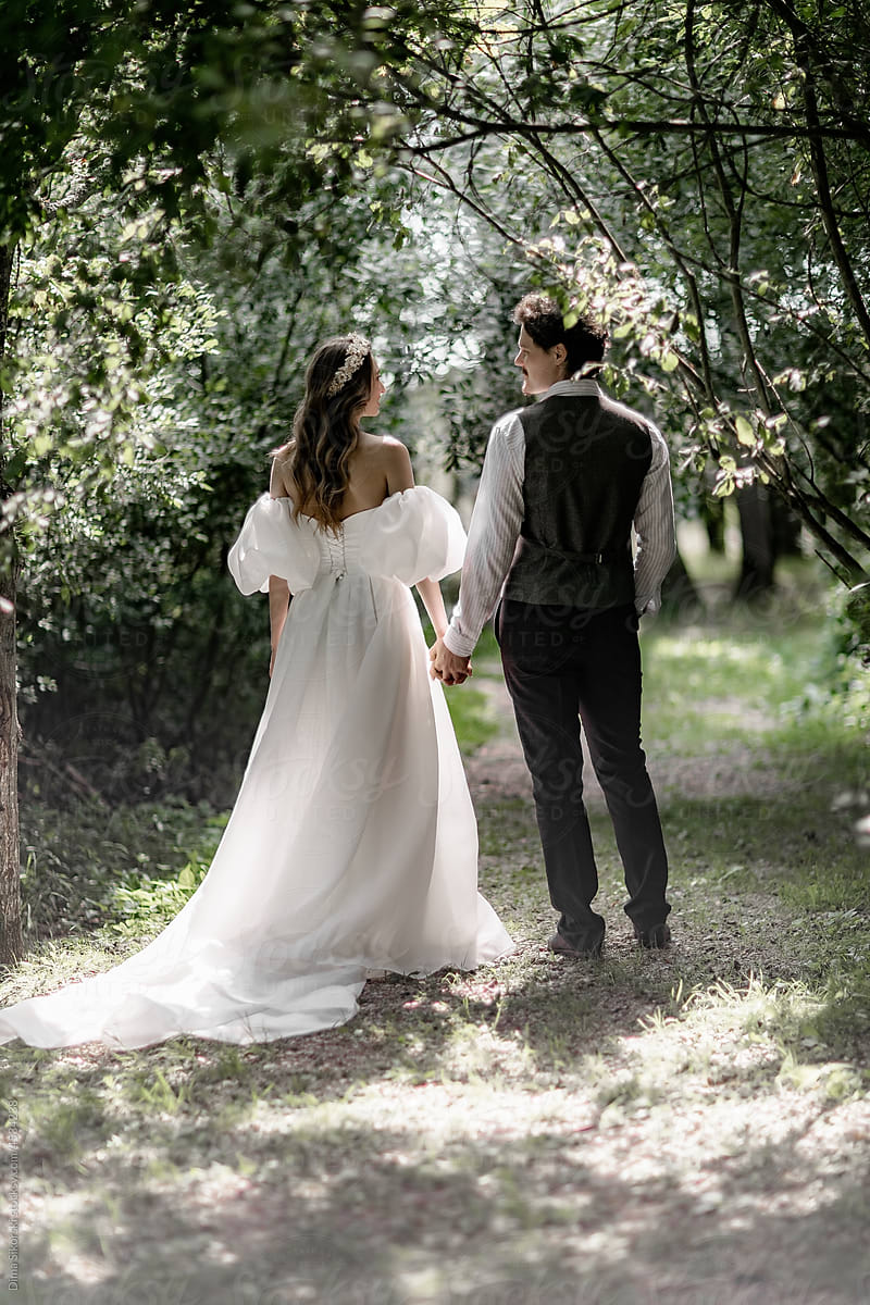 The bride in an elegant wedding dress with the groom in the sunlight