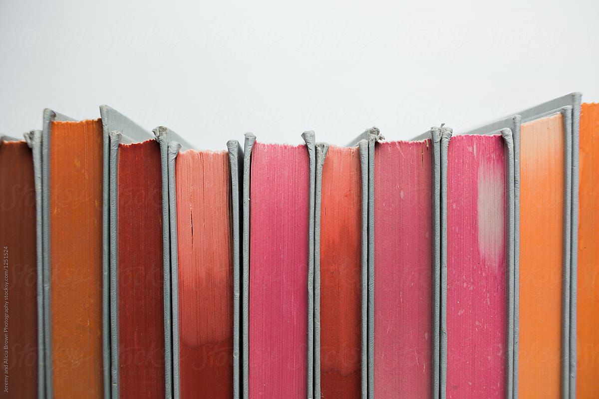 Stack of vintage books with orange, pink, and red pages