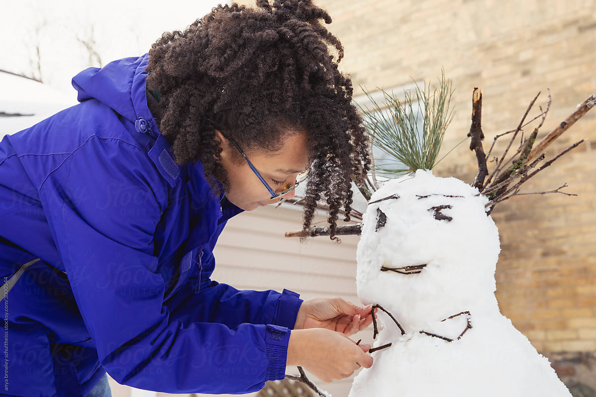 Teenager building a snowman on a cold winter day
