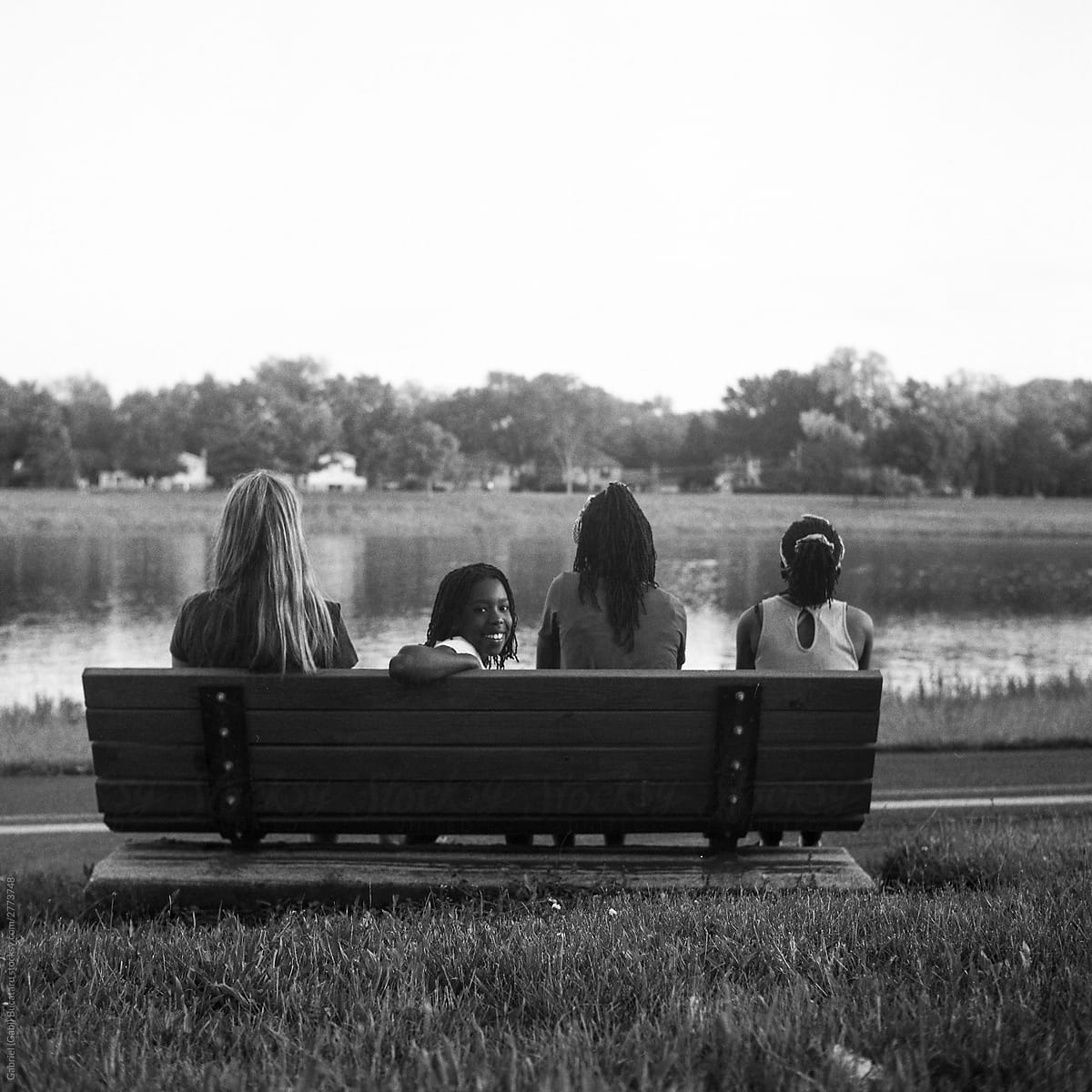 Mixed race family sitting on a bench by a lake
