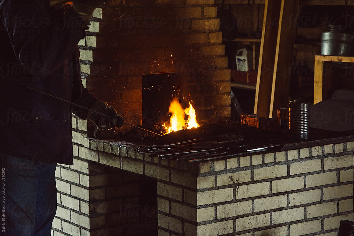 Blacksmith forging a metal rod on a fire