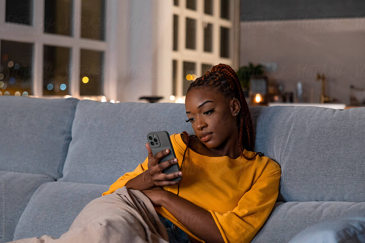 Bored black woman browsing smartphone at home