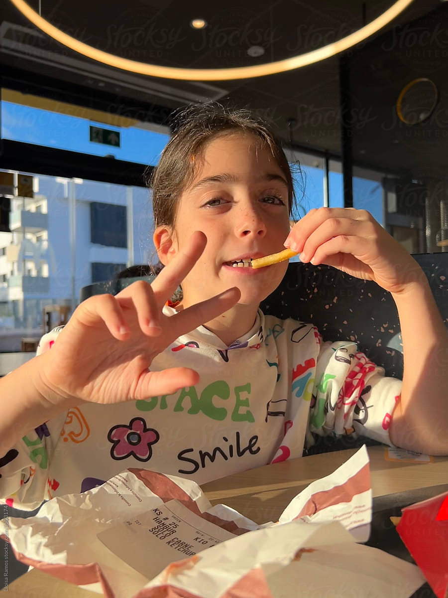 kid girl eating French fries at restaurant