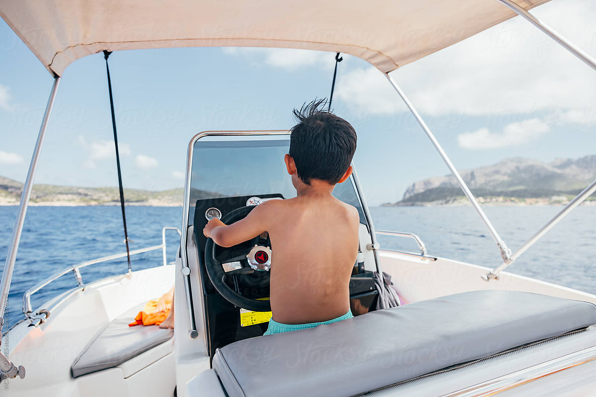 Kid driving a small yacht in the sea