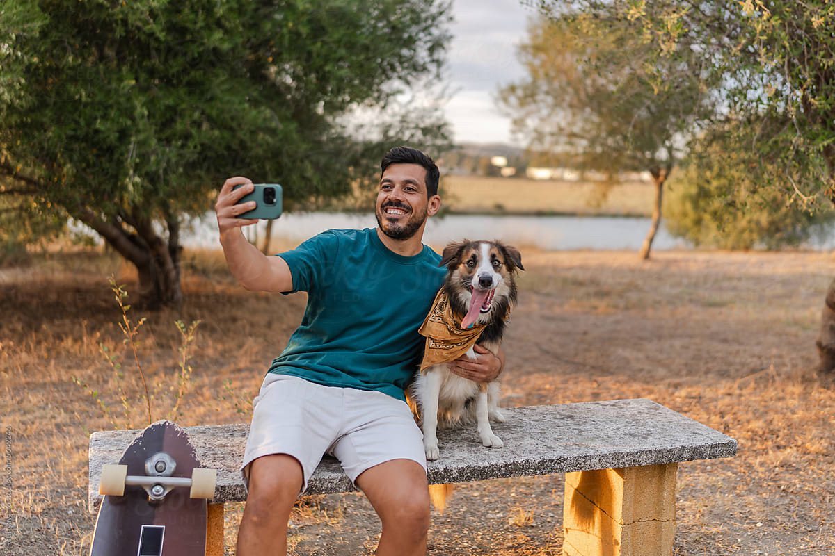 man taking a selfie with his dog in the park