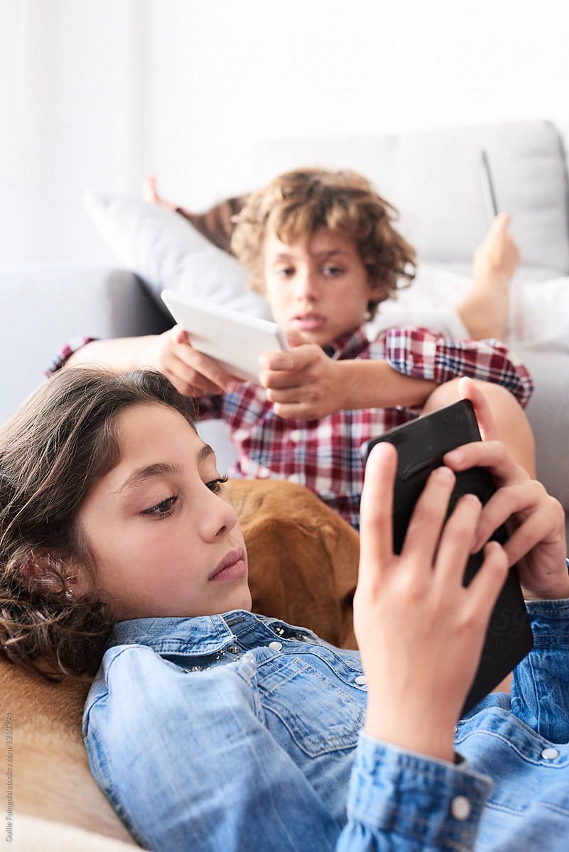 Kids and mother using gadgets in living room.
