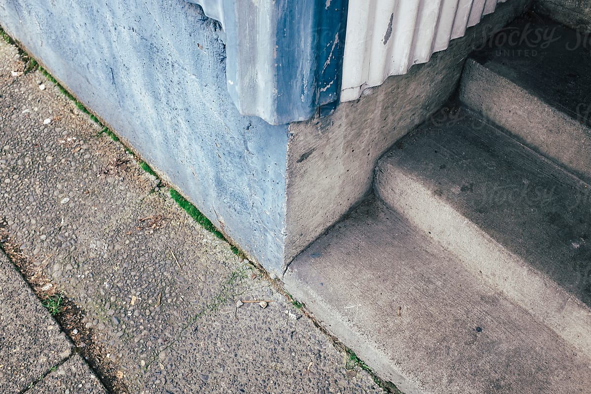 Painted blue corner of building wall and urban sidewalk