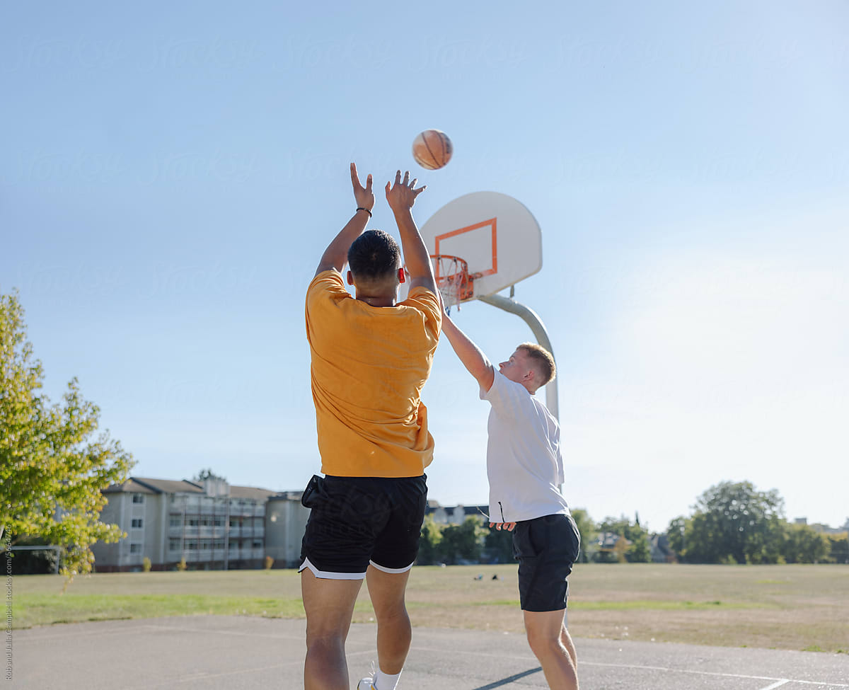 Two men playing one-on-one basketball together outside.