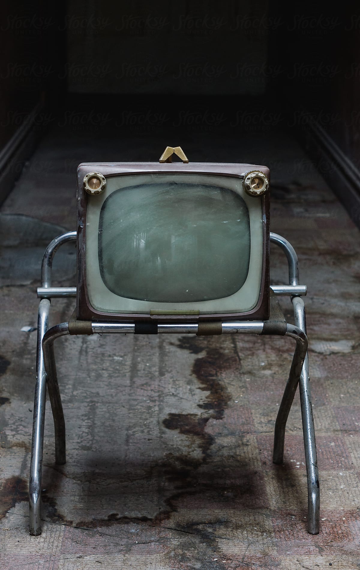 vintage tv left on stand in deserted hallway
