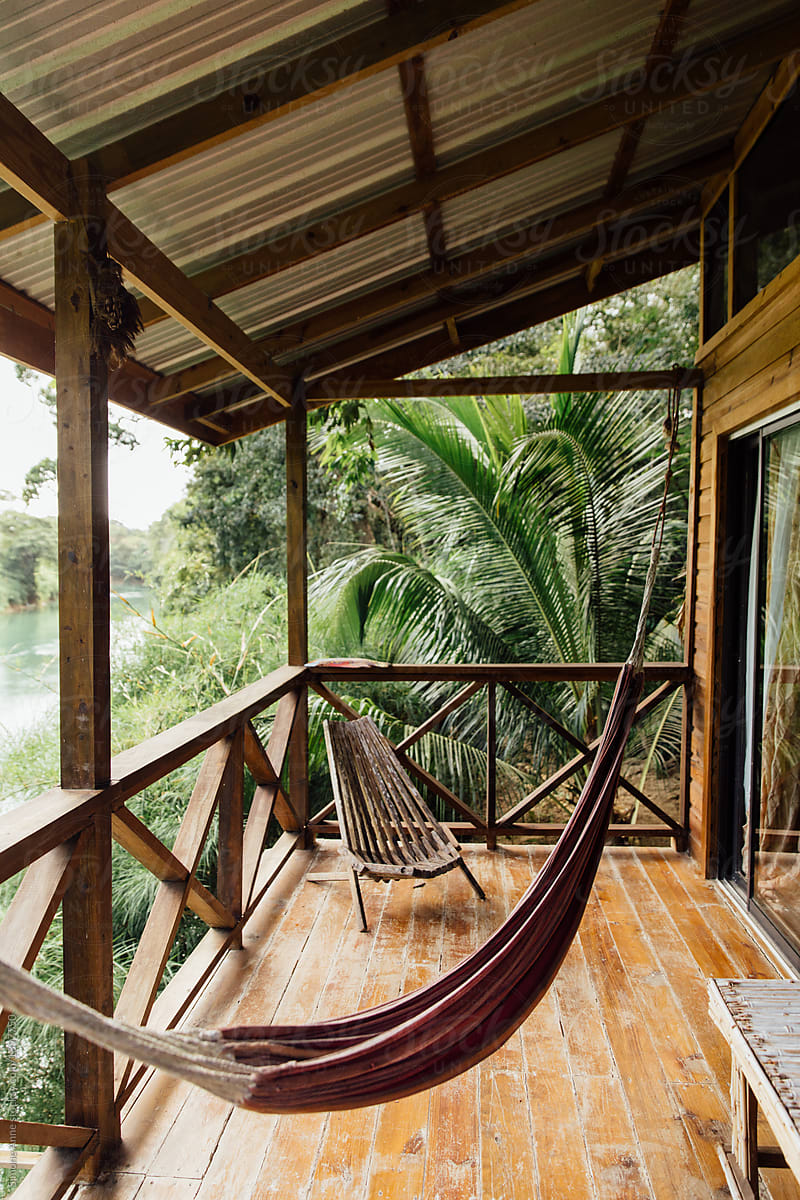 Hammock hangs on the deck of a cabin next to the river