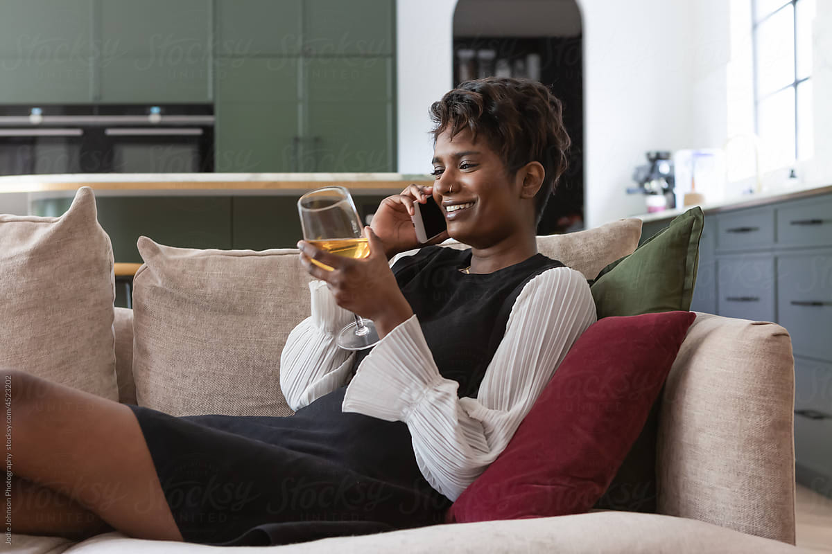 Woman chatting on the phone with glass of wine at home
