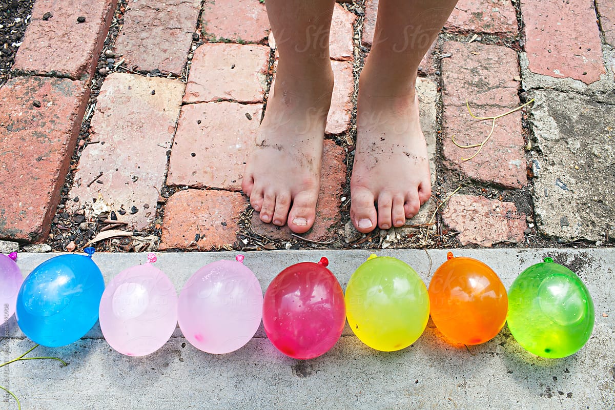 child\'s feet with colourful water balloons lined up ready to attack