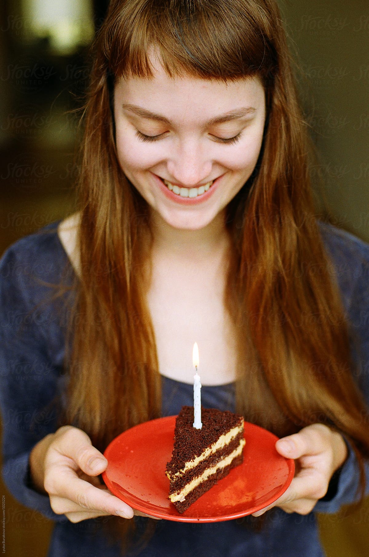 Happy young woman holding a piece of birthday cake