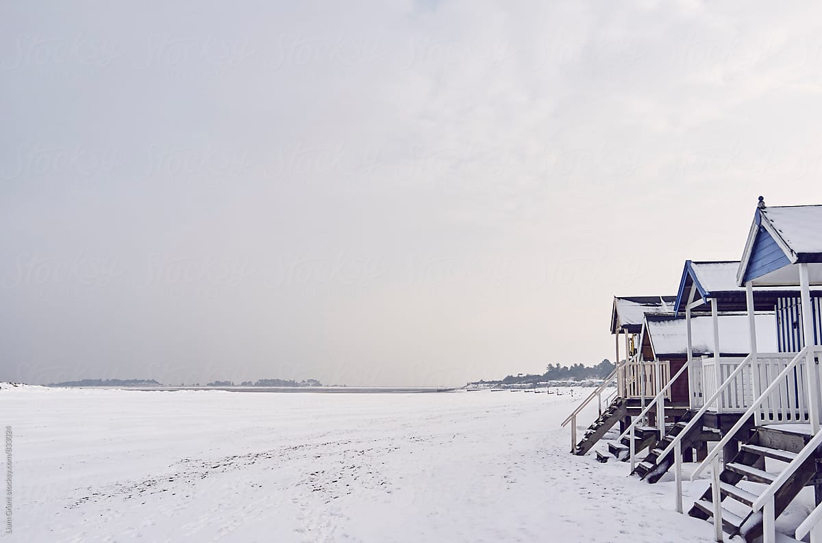 Beach huts covered in snow at low tide. Wells-next-the-sea, Norfolk, UK.