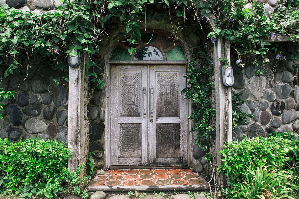 Vines and flowers adorn a wooden door side entrance of a chapel on a hill