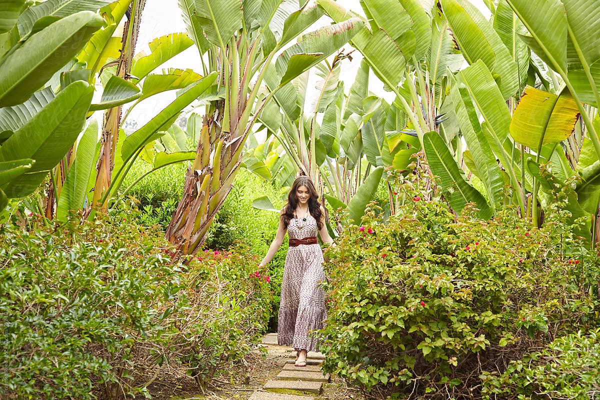 Happy woman walking on pathway on vacation at luxury tropical resort