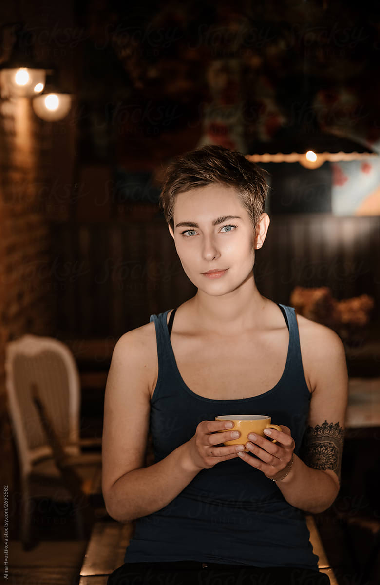 Portrait of beautiful female in top holding cup of coffee.