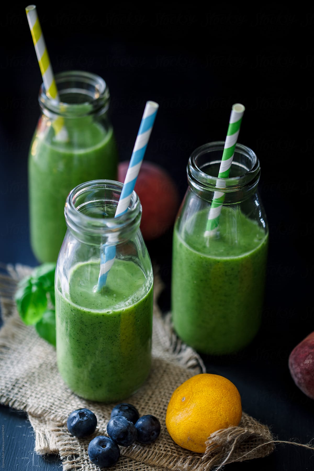 Detox smoothies in glass bottles with straws.