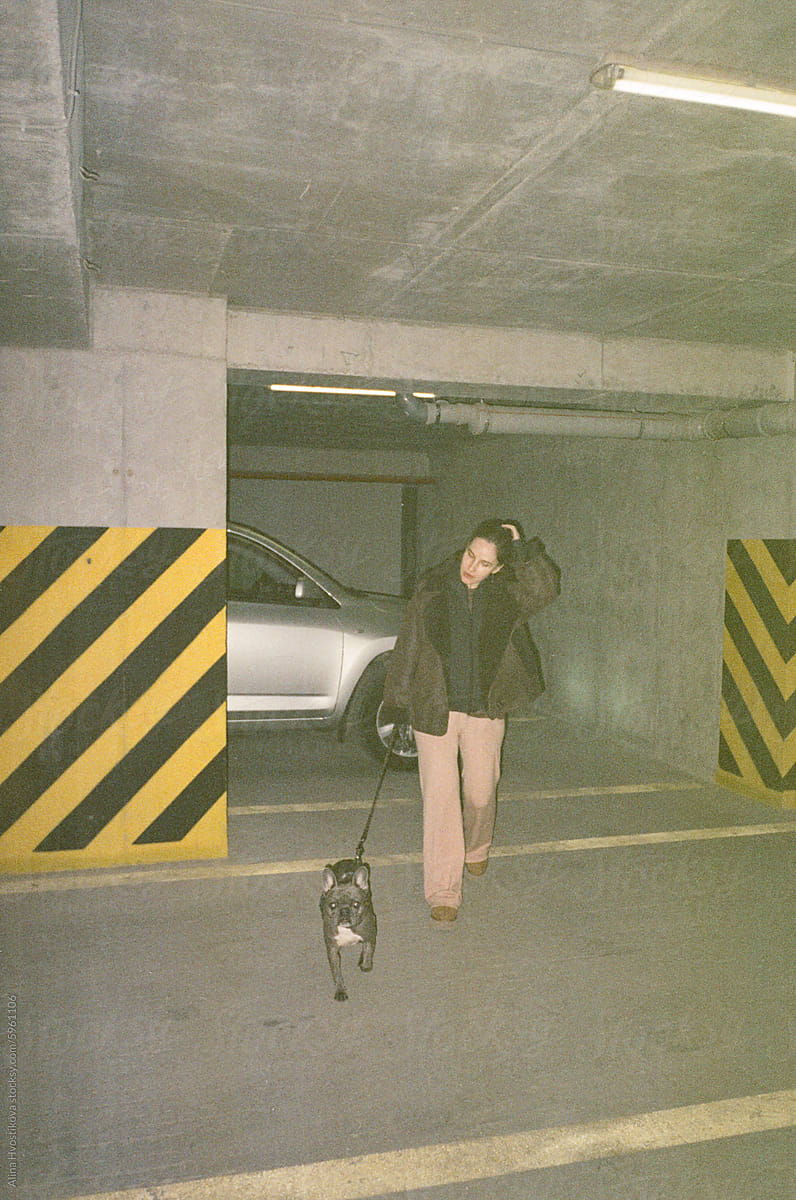 Young woman walking with dog in parking lot