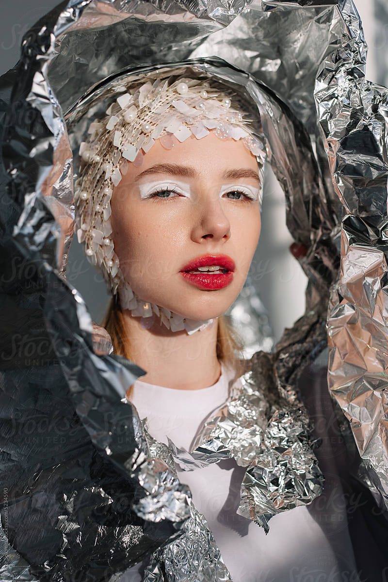 Young woman in bright makeup and standing with foil