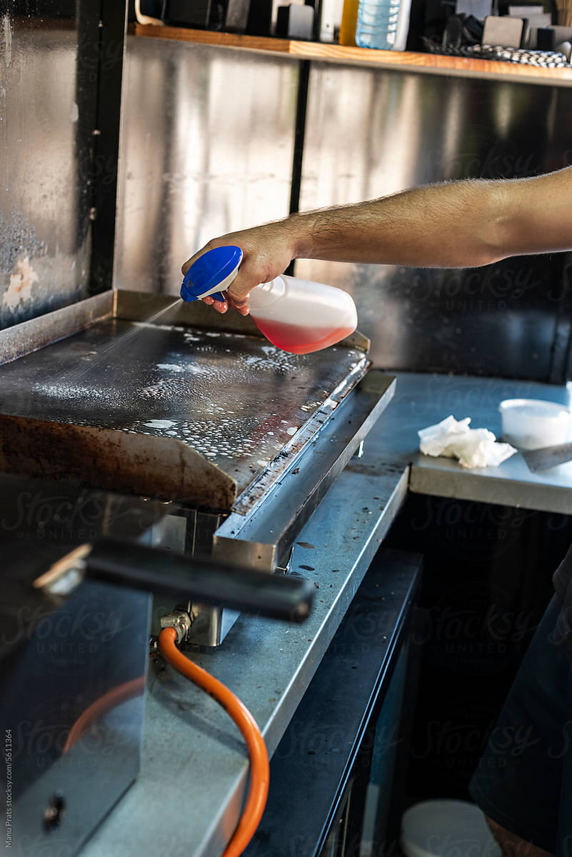 Chef cleaning cooking griddle in a small business food truck