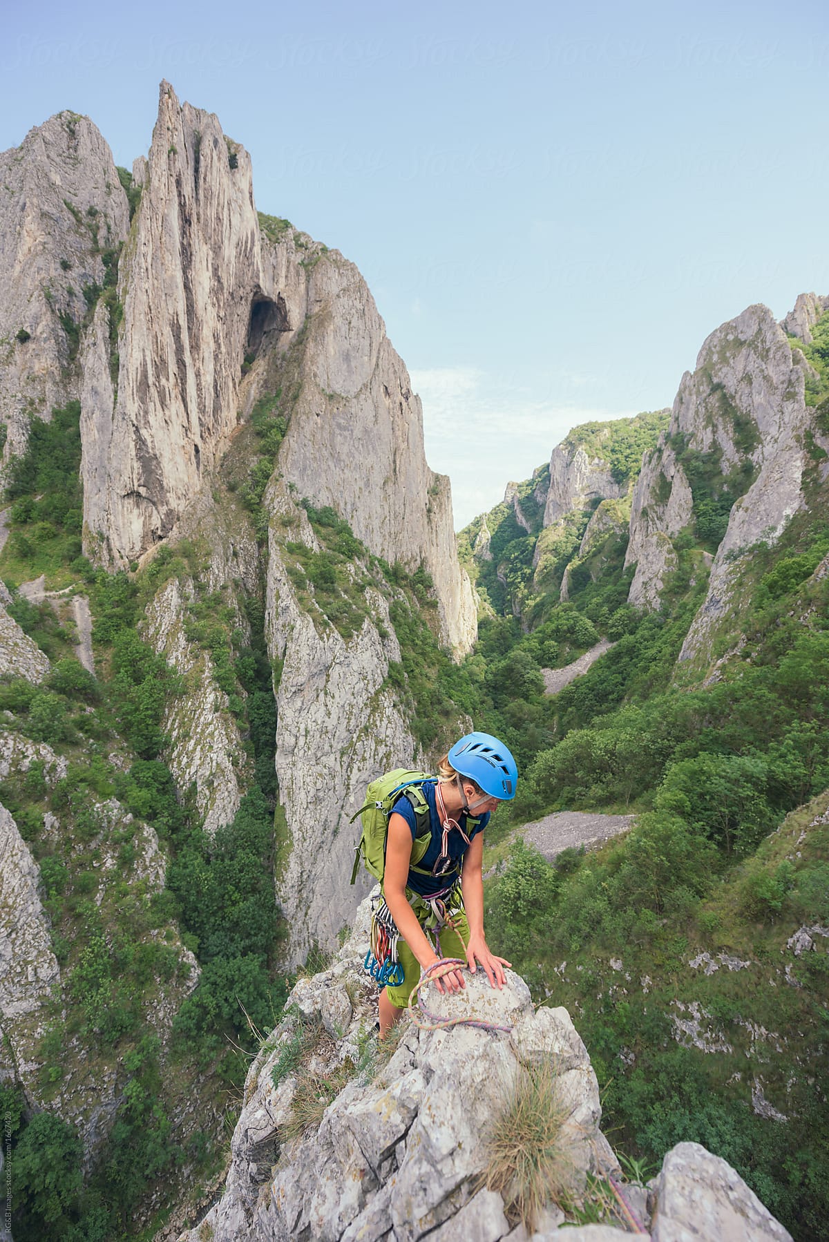 Female rock climber descending off craggy cliff