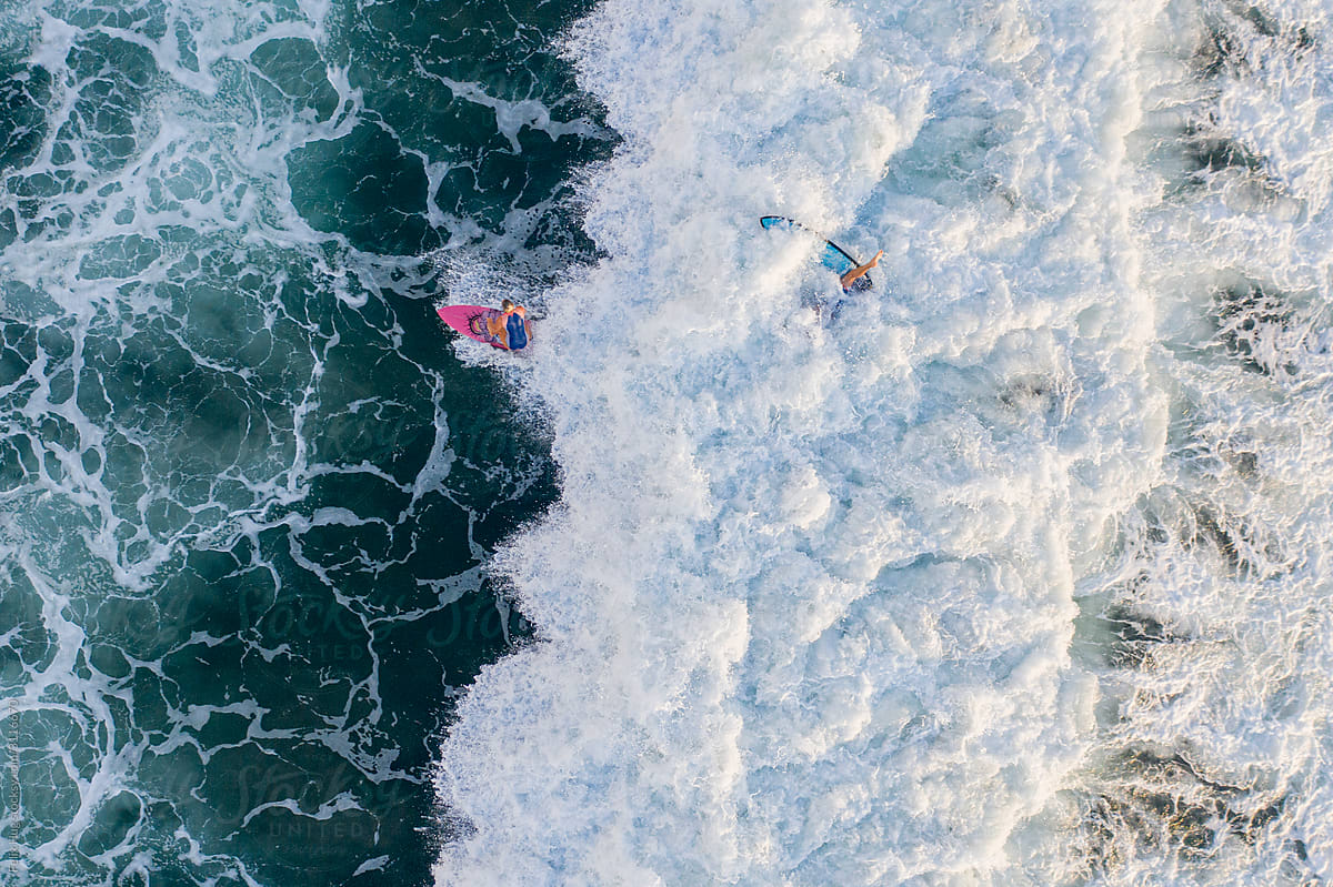 Female surfer in the waves in Bali seen from above
