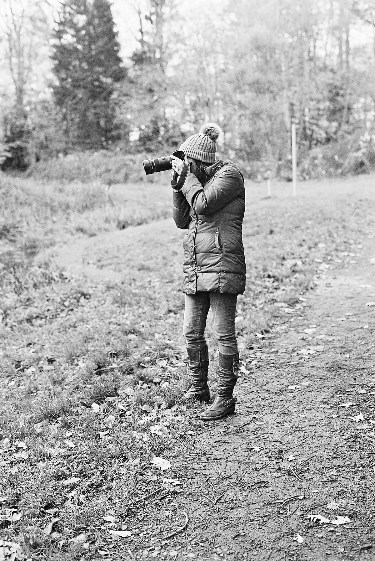 Female in winter clothing taking a photography outdoors with a dslr camera.