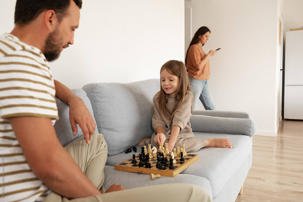 Cheerful kid playing chess with dad