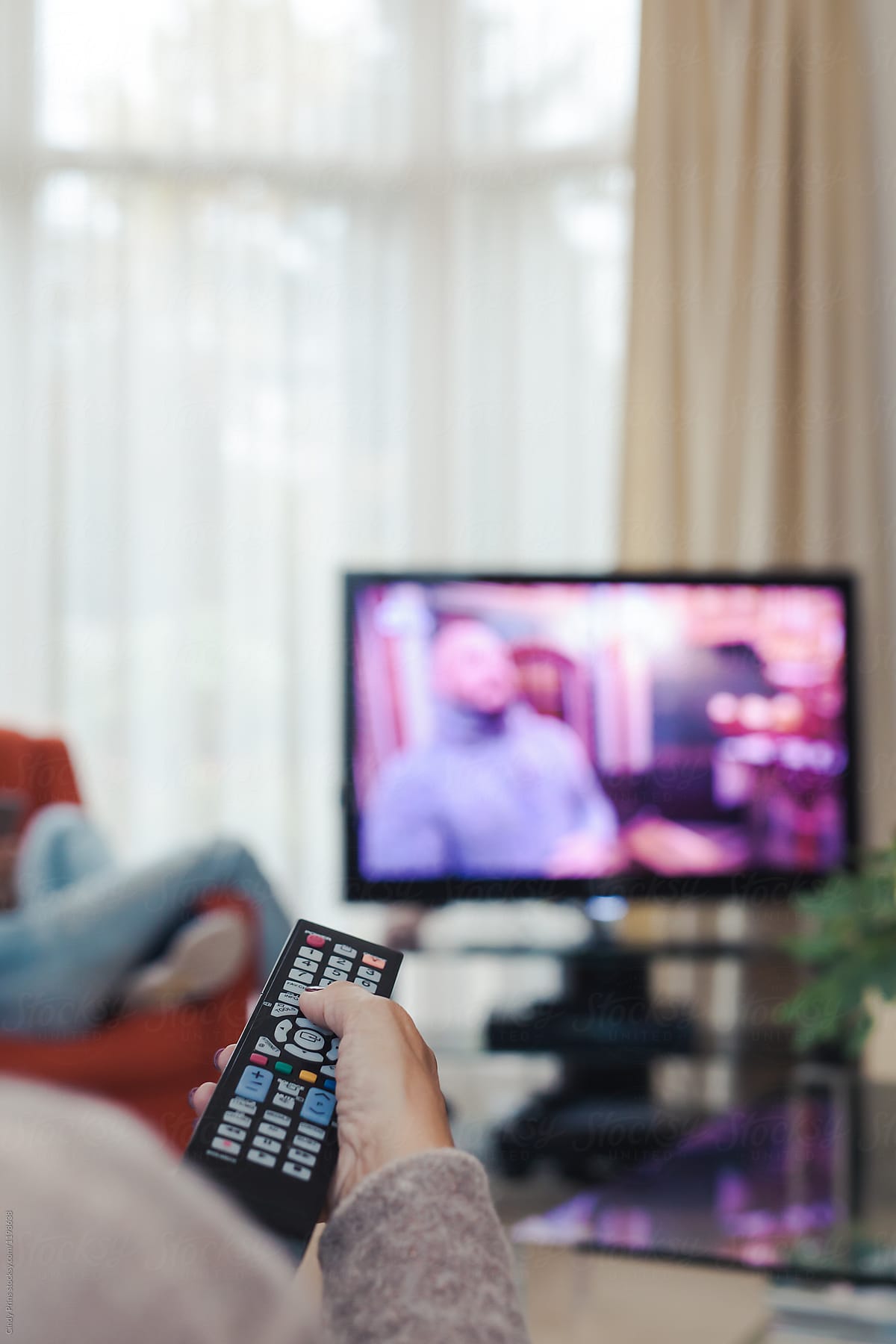Closeup of a lady\'s hand holding the remote control of the tv