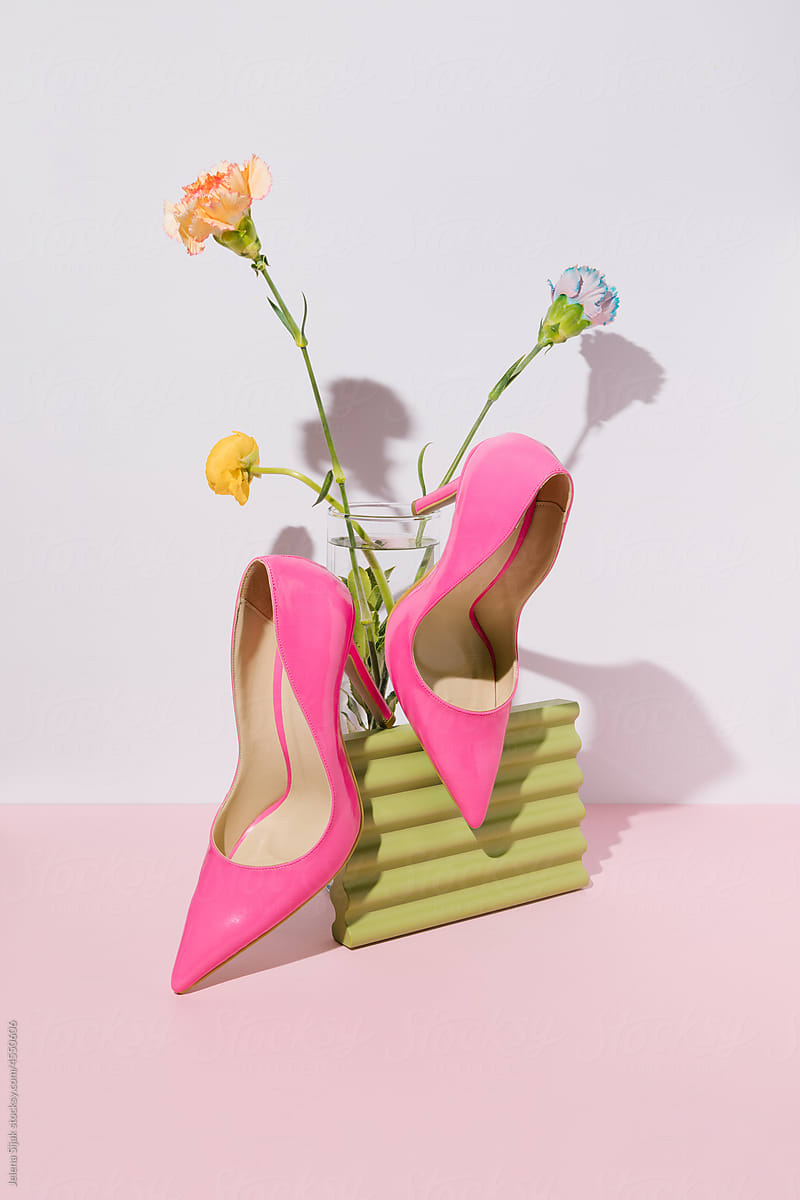 Female high heel pink sandals and various vibrant blooming flowers.