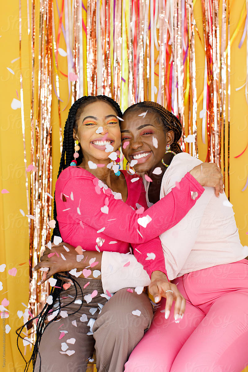 Two laughing happy women with pink confetti