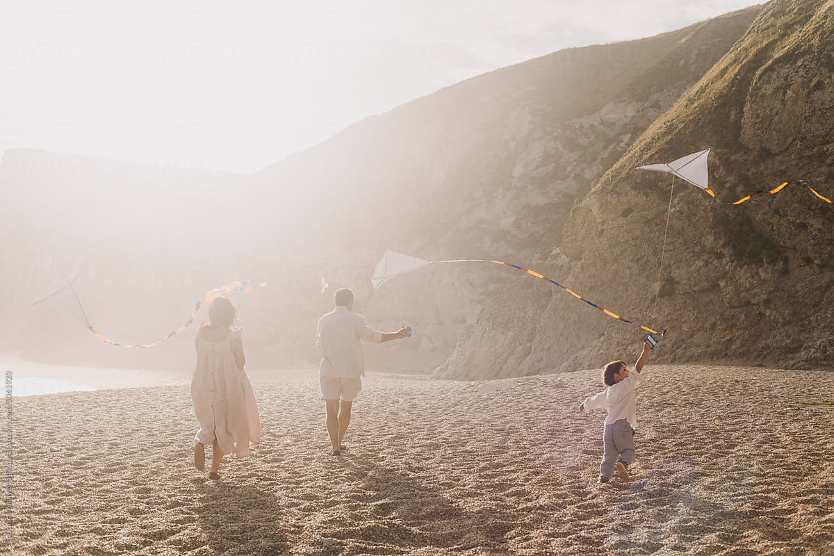 Happy Family Playing With A Kite, Having  Fun together Near Ocean