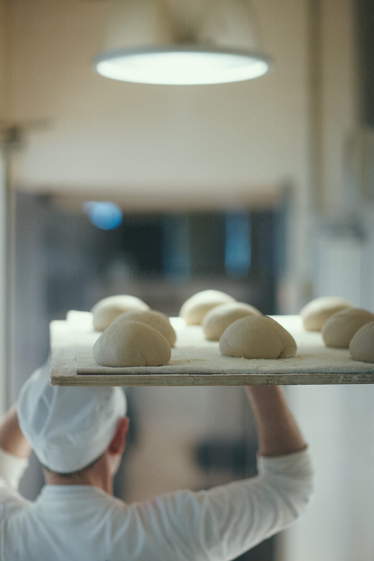 Baker with bread buns dough on a tray