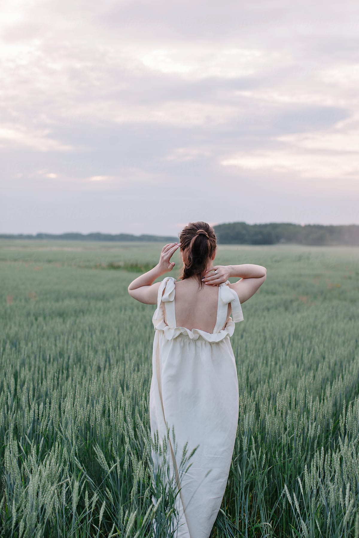 Anonymous woman in white dress in field