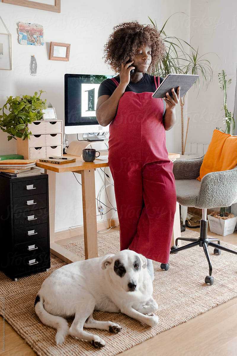 Pregnant woman working in home office with dog