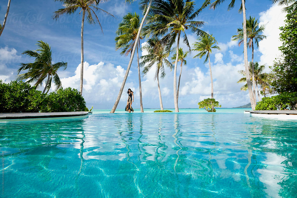 Woman Walking By Infinity Pool On Vacation At Luxury Resort By Trinette