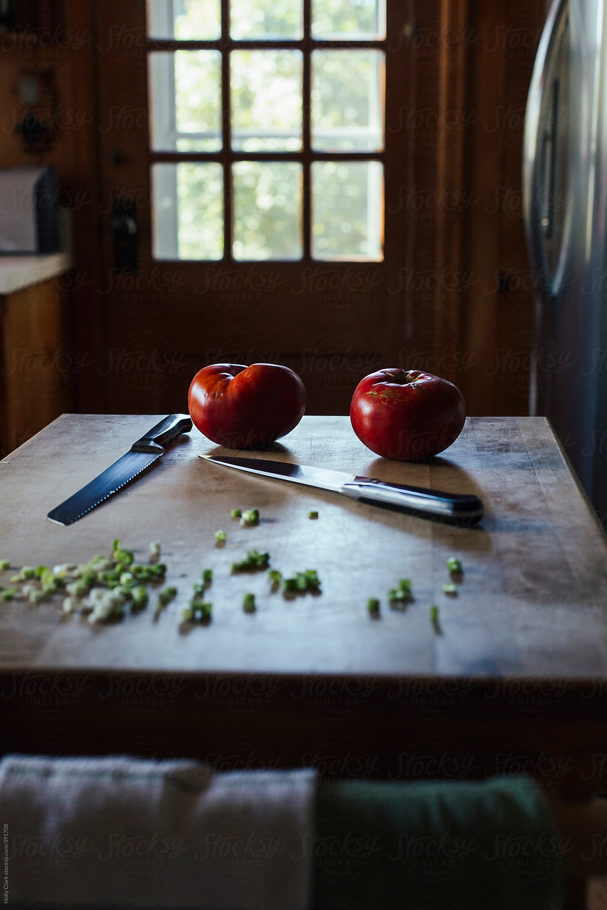 Homegrown tomatoes and chopped green onions on a butcher block