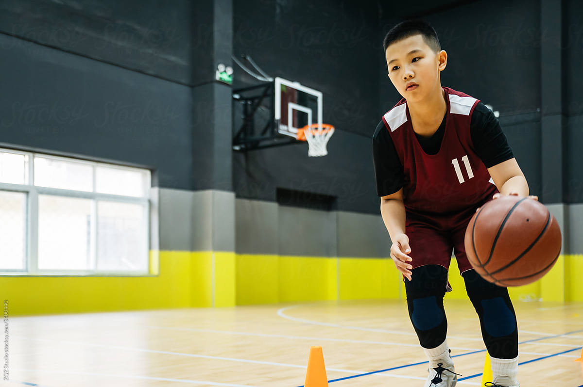 Teenage boy wearing basketball uniforms and doing drills at practice
