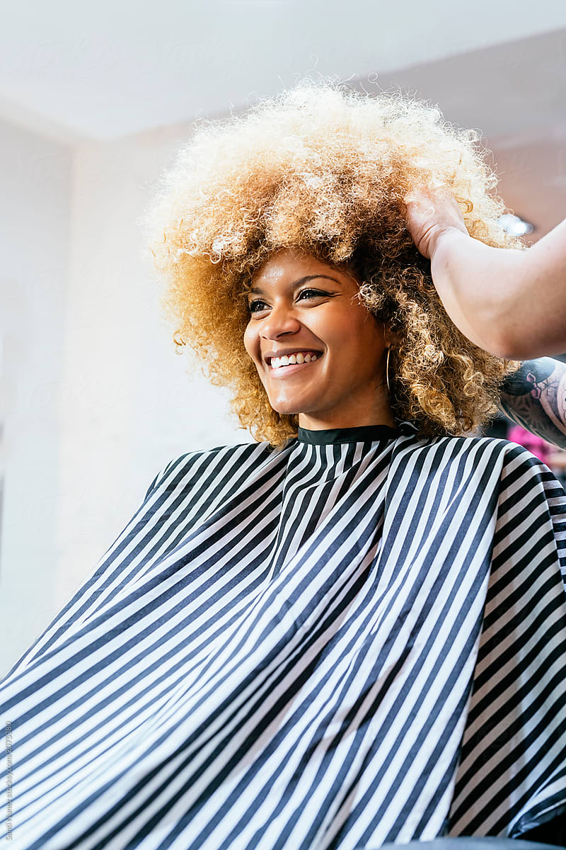 Beautiful afro woman getting haircut by hairdresser in the beauty salon